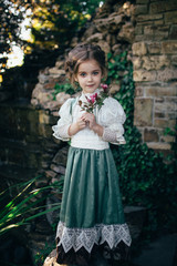 girl in a green-white dress holds a flower in her hands