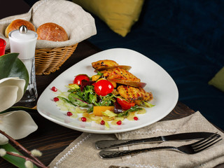 Delicious slices of fried chicken breast with pear and arugula salad on a restaurant table