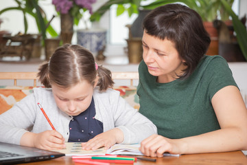 Study online with video call teacher. Young girl learn online and looking at laptop at home.Social distancing.