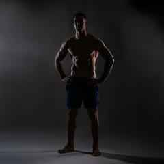 Naklejka premium Strong Athletic Man Fitness Model Torso showing six pack abs. isolated on dark background with copy-space