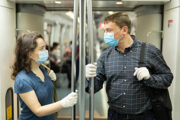 Man and woman in medical masks talking in subway