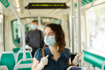 Female in medical mask holding on handrails in bus