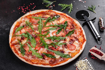 Fresh pizza baked in oven with arugula, salami, cherry tomatoes and mozzarella