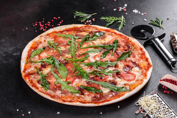 Fresh pizza baked in oven with arugula, salami, cherry tomatoes and mozzarella