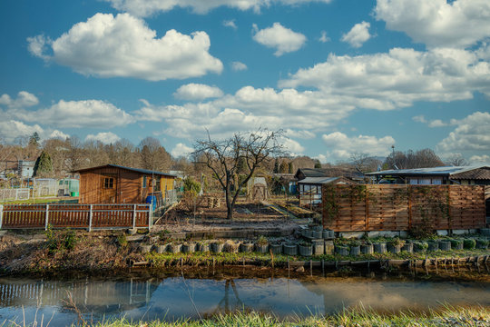 Schreberg&auml;rten an einen Bach im Herbst mit bew&ouml;lktem Himmel