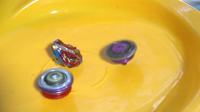 Collective image of the children's popular toy Beyblade. The battle of two Beyblade in the arena in a flat style.Slow motion.