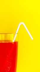 White plastic disposable straw in a red summer tasty cocktail on a yellow background. Refreshing drink. Hot season. Soft drink. Proper nutrition. Selective focus.