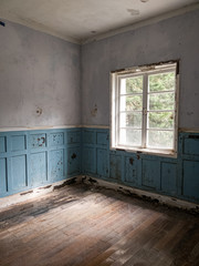 looking into a corner of an empty room with wooden floor & walls in an abandoned house