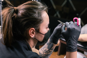 Female master uses an electric machine to remove the nail polish during manicure in the salon. Close-up hardware manicure. Concept of hand care. Female manicurist cleaning of nails by a milling cutter