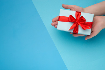 White woman holding a white gift box with a red bow on a blue one . Gift for birthday, Christmas, Valentine's Day, New year . Flat lay