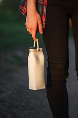 Eco-friendly bottle. Reusable white bottle with water on the finger of the hand. Folding bottle.