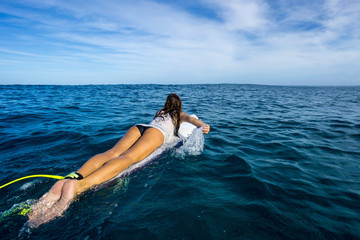 Beautiful slim girl surfer paddles on the wave in the open ocean. Mauritius Island