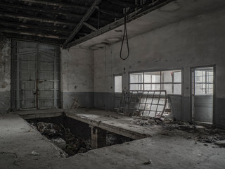 Interior de fabrica abandonada con ventanales y portón de entrada.