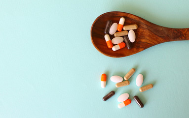 Assorted pharmaceutical medicine pills, tablets and capsules on wooden spoon