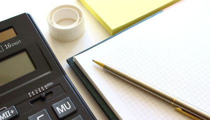 Calculator pen and notebook on white background