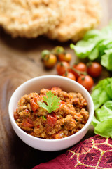 Northern Thai food (Nam Prik Ong), spicy chili minced pork with tomatoes in a bowl on wooden table eating with vegetables, Thai chili paste