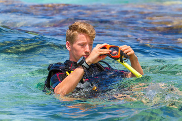 Young dutch diver in sea holding diving mask