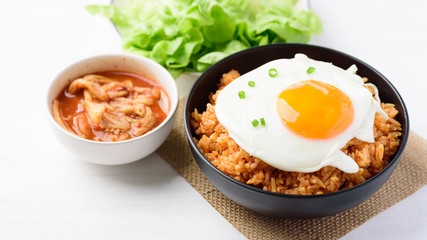 Kimchi fried rice with fried egg on top in a bowl and fresh kimchi cabbage, Korean food