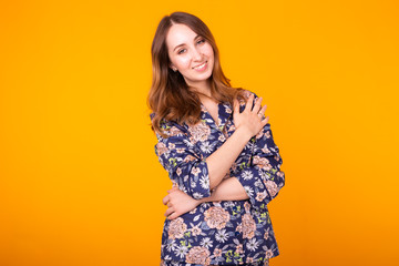 Excited young woman with curly hair in home wear pajama, widely smiling having fun. Isolated on yellow background.