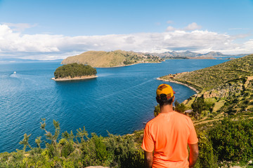 Fototapeta na wymiar Tourist MAN on Island at Isla del Sol in Bolivia. Scenic panoramic view of island and sea horizon. Bolivian island paradise and hills. Walking trail, by boat. Local community, tourism. Titicaca lake
