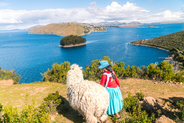 Girl and Llama Alpaca with Island on Isla del Sol in Bolivia background. Scenic panoramic view of...
