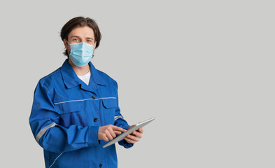 Young Quantity Surveyor Wearing Medical Mask And Using Digital Tablet