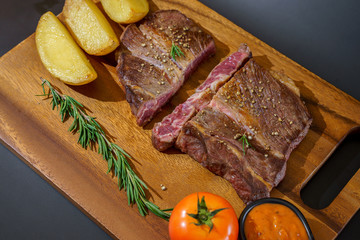 Succulent thick juicy portions of grilled fillet steak served with tomatoes and roast vegetables on an old wooden board