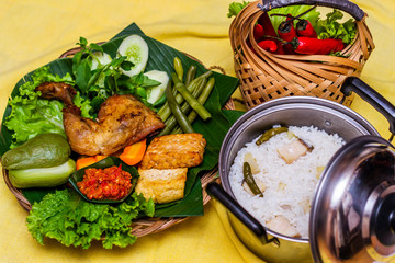 Indonesian traditional food nasi liwet with fried chicken, tahu, sambal and lalapan served with rice and assorted vegetables