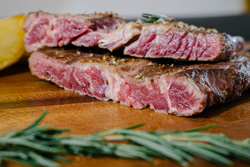 Succulent thick juicy portions of grilled fillet steak served with tomatoes and roast vegetables on an old wooden board