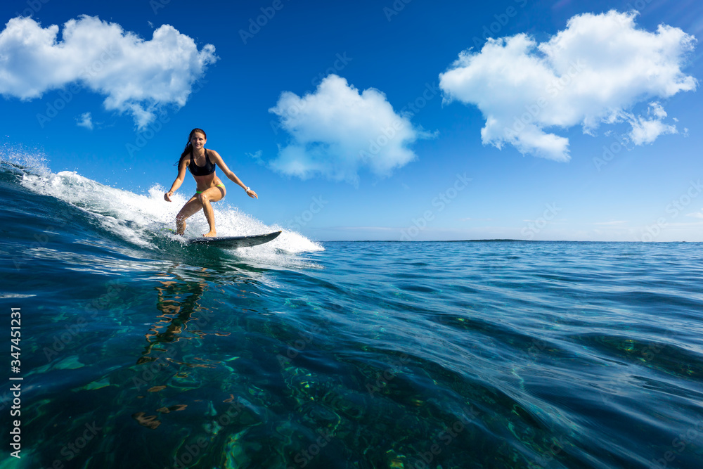 Wall mural young beautiful girl surf on the big waves in the open ocean. mauritius island