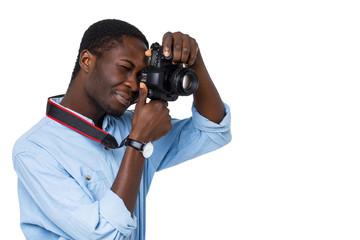 Young african man photographer focuses with professional DSLR camera on isolated white background