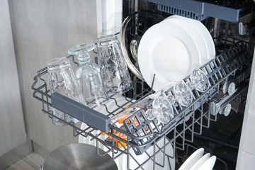 Dishwasher, open and loaded with dishes in the kitchen, after washing, close-up.
