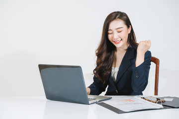 Successful girl manager in her own office makes a new economic development business plan on a laptop . A business woman with documents sits at a wooden table