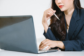 Close-up Asian businesswoman holds a pen and clicks the keyboard.
Young business women use computers