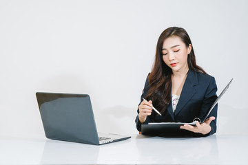 Successful girl manager in her own office makes a new economic development business plan on a laptop . A business woman with documents sits at a wooden table