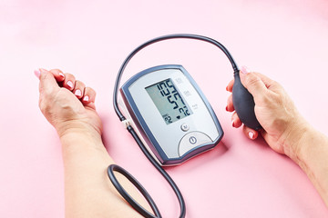 measuring blood pressure with electronic medical device over pink background