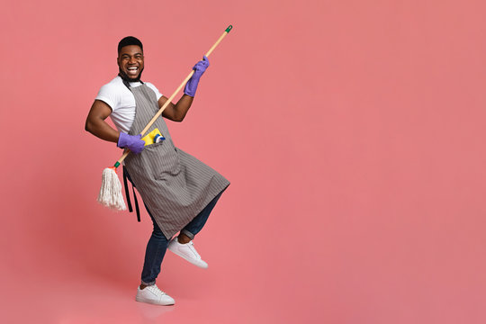 Funny African Man Using Mop Handle As Guitar, Having Fun During Cleaning