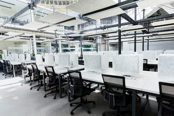 Big empty rental office for IT workers with wrapped in cover computers