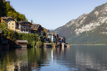 Fototapeta na wymiar Traditional Austrian houses built on hillside surrounded by natural lake and mountains in the Alps