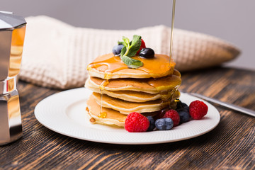 Woman pouring maple syrup on tasty pancakes.
