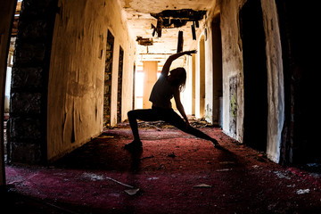 Sporty woman performing yoga exercises in different locations (on a dilapidated construction site)