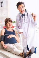 Young doctor checking pregnant woman's blood pressure