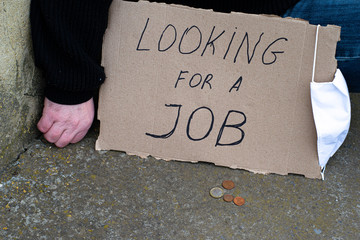 Unemployment concept and unemployed coronavirus sitting on the ground next to it a cardboard plate...