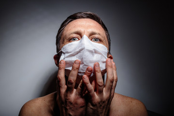 Masked man in twilight, scared, close up, hands on face