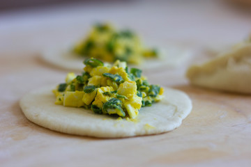 yellow-green filling for pies on pastry on a wooden board, dough stuffed with green onions and boiled eggs, Russian cuisine, rustic food, pies with onions and eggs, the preparation of pies