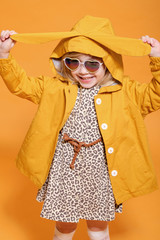 funny girl in yellow raincoat with rabbit ears on yellow background