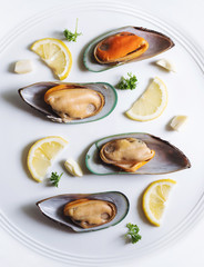 New Zealand Mussels with slices lemon, parsley and garlic, on white ceramic dish