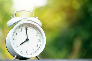 Retro white alarm clock on wooden table, vintage style
