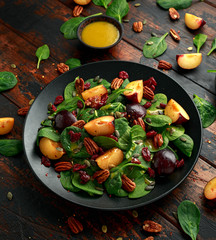 Vegan plums salad with cranberry, pumpkin seed, pecans nuts, spinach and mustard dressing