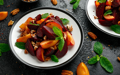 Vegan Plum, beet salad with pecan nuts, mint and herbs on rustic black table